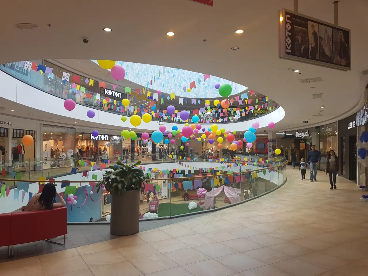 Atrium i to etager i Mall of Split med farverig hængende pynt, butikker og siddepladser