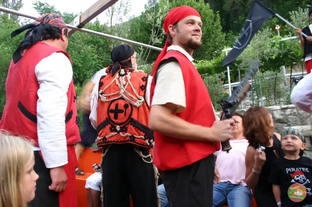 Costumed Omiš pirates in red waistcoats and bandanas entertaining passengers on a boat