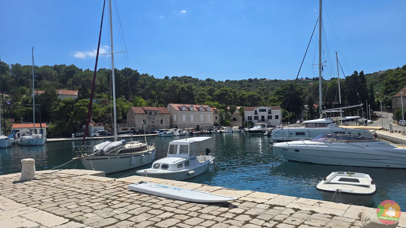 Harbour in Rogač on Šolta with sailboats, motorboats and old stone houses among pine trees