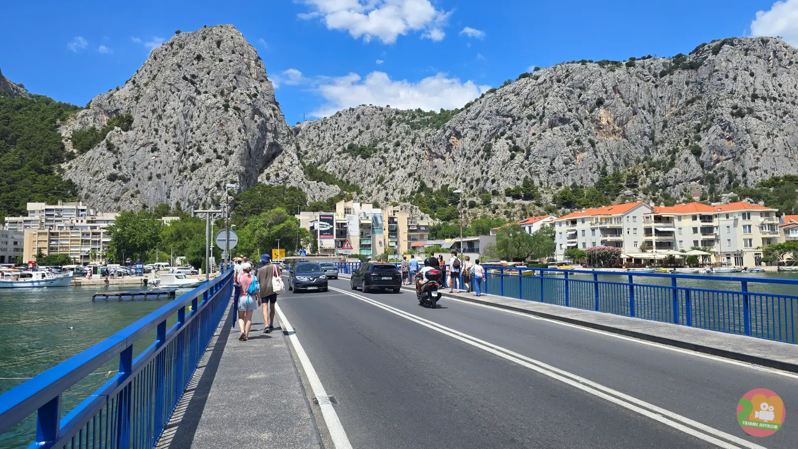 Broen over floden Cetina i Omiš med fodgængere, biler og stejle kalkstensklipper i baggrunden