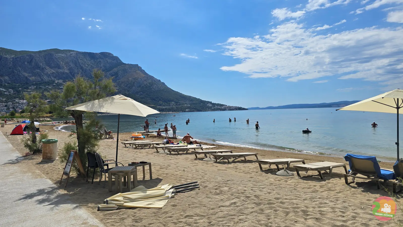 Sandstrand Galeb in Omiš mit Sonnenschirmen, Liegen und Bergen im Hintergrund