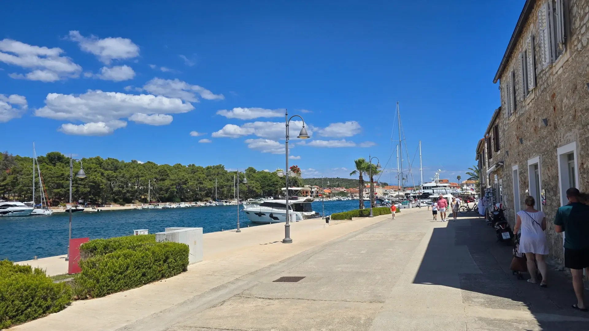 Stari Grad promenade with stone houses on one side and motor yachts moored along the bay on the other