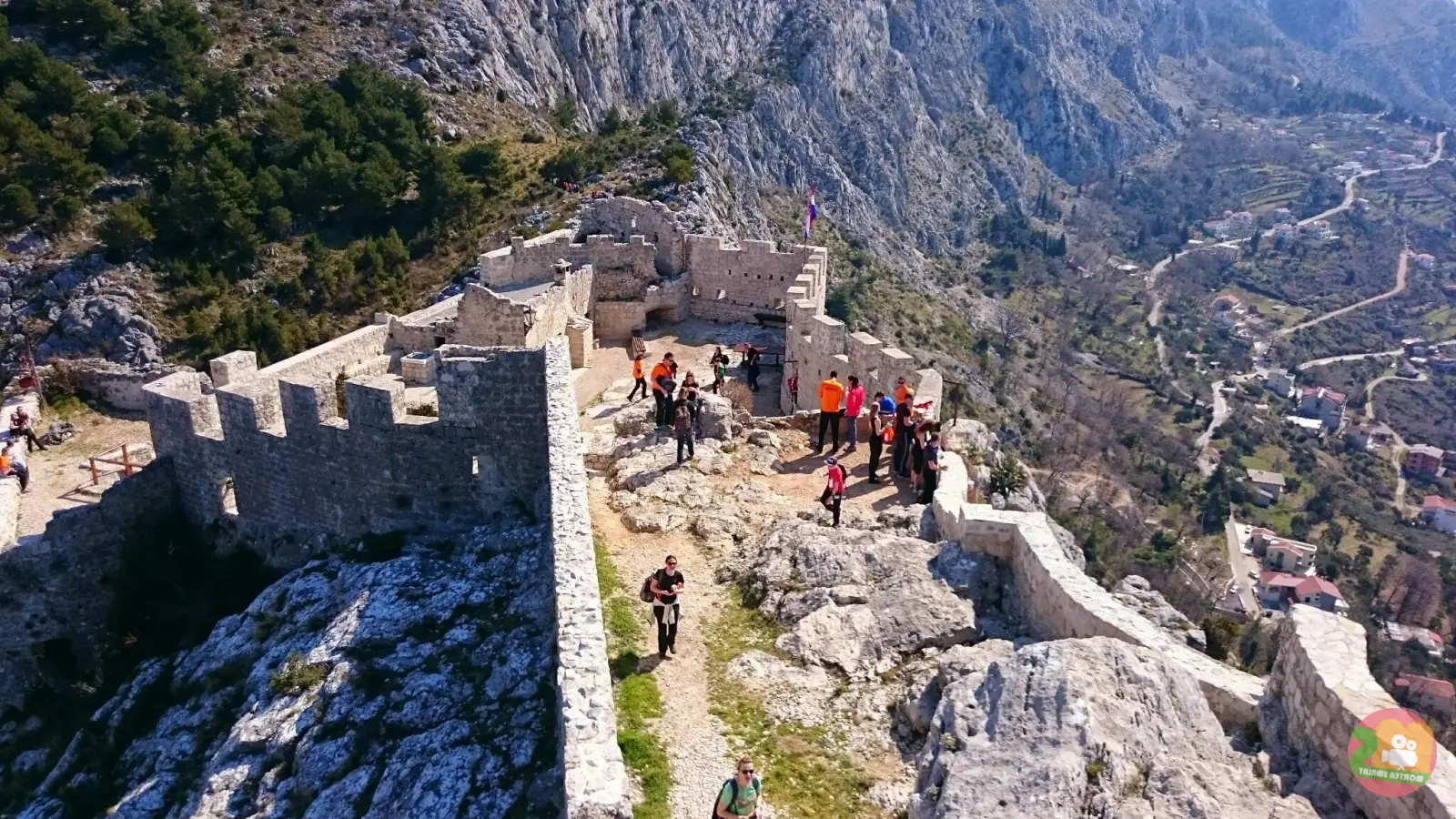 Pogled iz zraka na tvrđavu Fortica Starigrad iznad Omiša s kamenim zidinama, posjetiteljima i obronkom