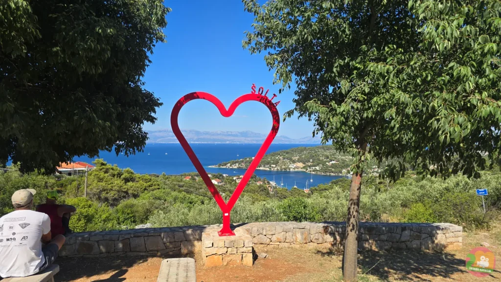 Rote Herzskulptur mit dem Schriftzug Šolta an einem Aussichtspunkt über dem Meer und der grünen Küste
